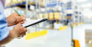 logistics service man writing documents on clipboard in warehouse