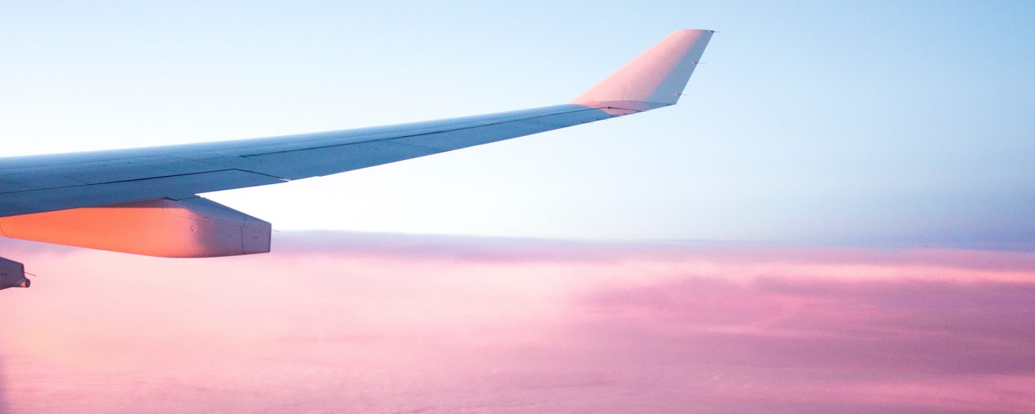 wing of airplane over pink clouds