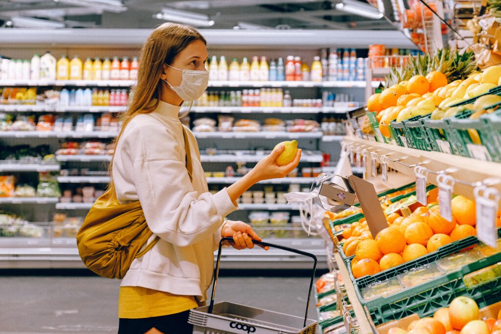 A woman holding a lemon in the produce section of the grocery store