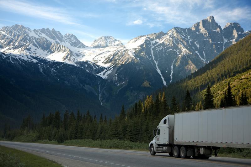An Image of a semi truck driving in a mountain range