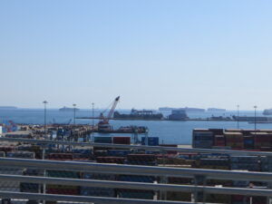 A photo of a port with cargo containers stacked high. The image conveys the importance of efficient and reliable drayage services for transporting freight between ports, warehouses, and distribution centers.